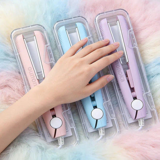 Three hair straighteners in clear packaging with a hand touching the pink one on a soft, multicolored background.