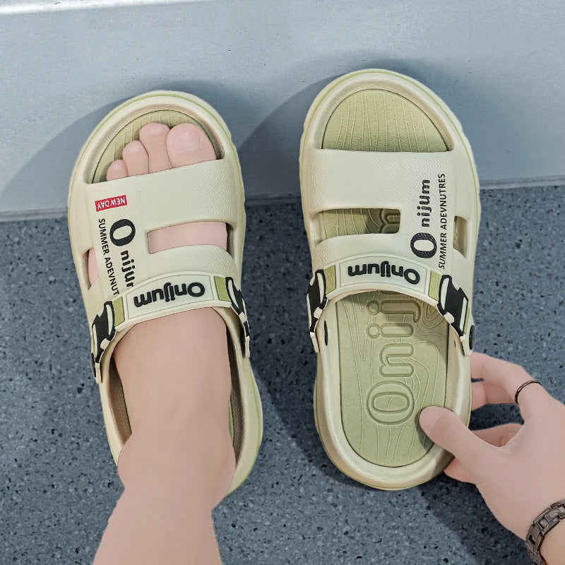 Beige sandals with 'omium' branding on a gray floor.