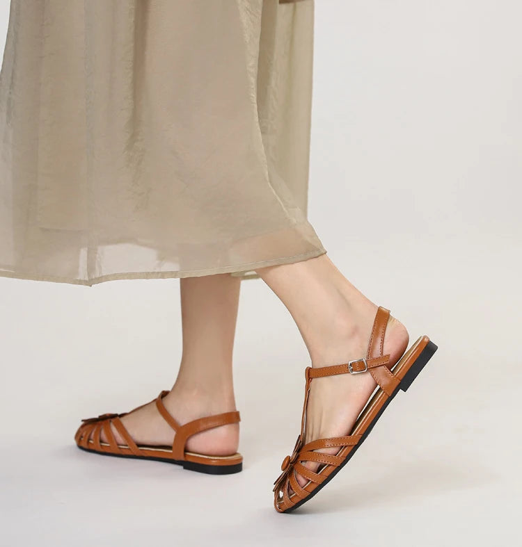 Brown sandals worn with a beige skirt on a light background