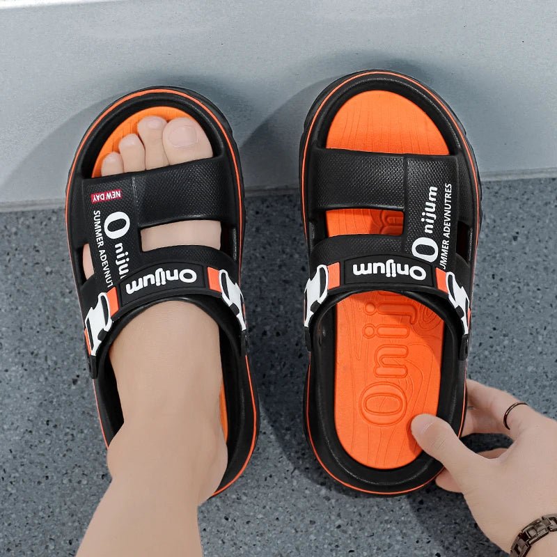 Black and orange sandals with 'Onium' branding on a gray floor.