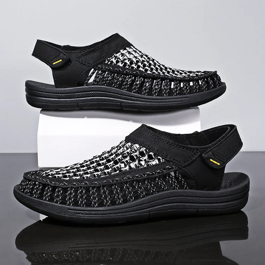 Black sandals with patterned straps on a reflective surface and light gray background