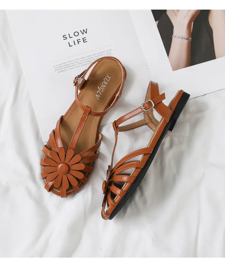 Brown sandals with floral design on a white surface