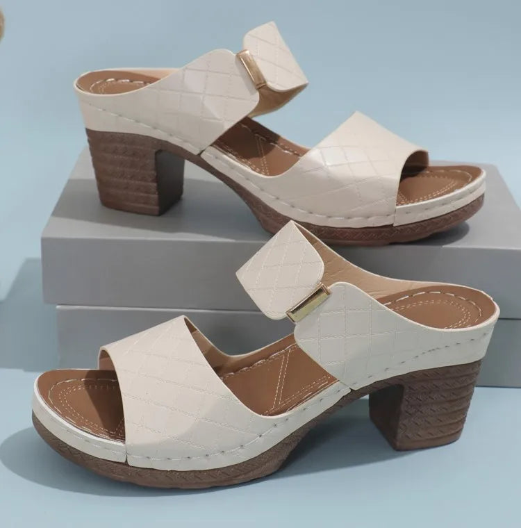 Pair of beige sandals with brown soles on a light blue background