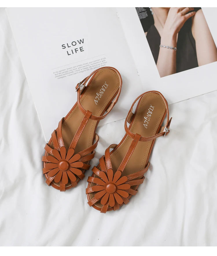 Pair of brown sandals with floral designs on a white background
