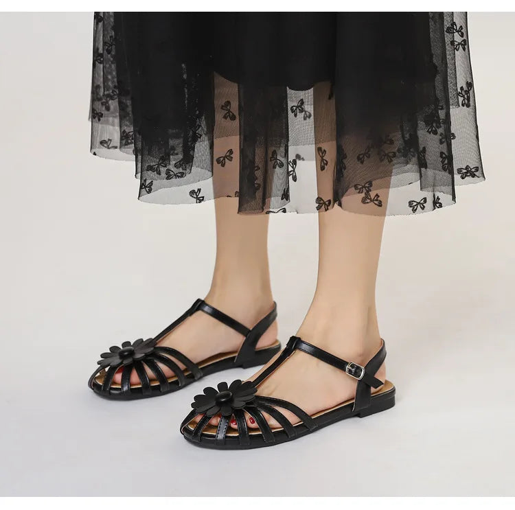 Black sandals worn with a black dress on a white background