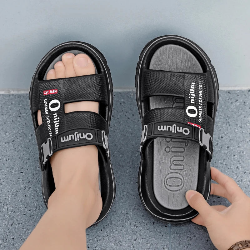 Black sandals with 'Onium' branding on a gray surface