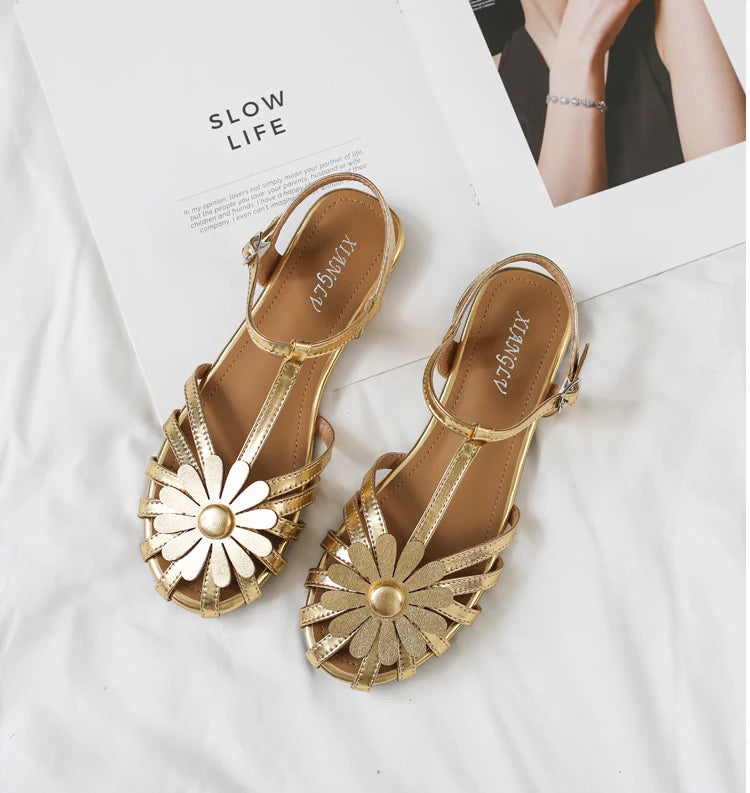 Gold sandals with floral design on a white background