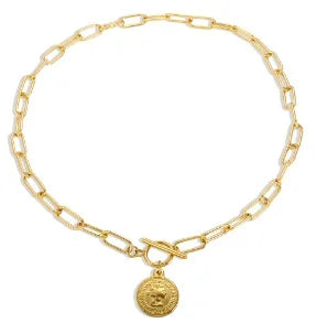 Gold chain bracelet with a round pendant on a white background